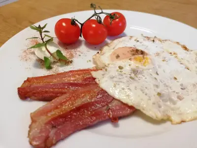 a plate of breakfast food with eggs bacon and tomatoes at Prenočišča Mraz in Velenje
