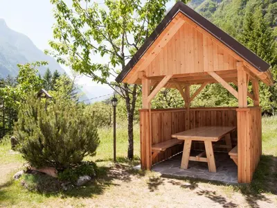 a wooden gazebo with a bench in a yard at Apartments and rooms Kravanja in Trenta