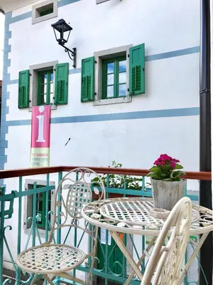 a table and chairs on a balcony with green shutters at Hisa Rejmr with private parking in Kobarid