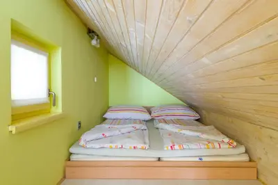 a bed in a small room with a wooden ceiling at Outstanding Lake View. in Kranjska Gora