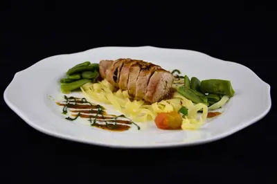 a plate of food with a piece of meat and pasta at Hotel Dolenjc in Novo Mesto