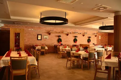 a restaurant with white tables and chairs and a brick wall at Hotel Dolenjc in Novo Mesto