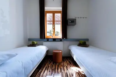 two beds in a room with a window at CUBE central rooms for 2 in Ljubljana