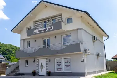 a white building with a balcony on top of it at Apartments Ema in Podčetrtek