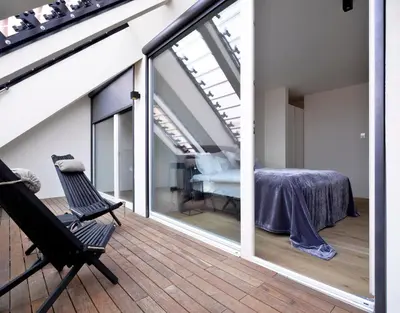 a room with a balcony with a bed and windows at Hotel Maribor, City apartments in Maribor