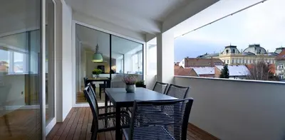 a balcony with a table and chairs and a view of the city at Hotel Maribor, City apartments in Maribor
