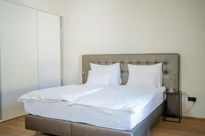 a large bed with white sheets and pillows at Hotel Maribor, City apartments in Maribor