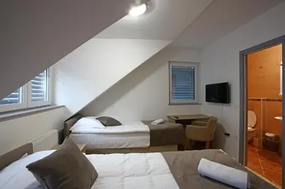 a bedroom with two beds and a table with a television at Gostilna in prenočišča Gedžo in Novo Mesto