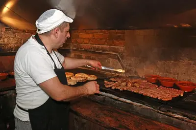 a man is cooking food on a grill at Gostilna in prenočišča Gedžo in Novo Mesto