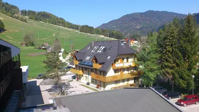 a large house with a black roof on top of it at Apartment Maša in Kranjska Gora