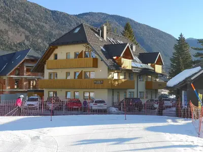 a large building with cars parked outside of it in the snow at Apartment Maša in Kranjska Gora