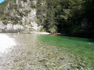 a river with green water and a rocky shore at Apartments Green Paradise in Bohinjska Bela
