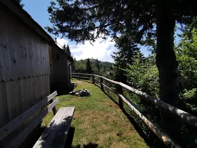 a wooden bench sitting next to a fence at Chalet Košutnik Velika planina in Kamniška Bistrica