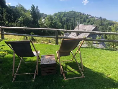 two chairs sitting in the grass next to a fence at Chalet Košutnik Velika planina in Kamniška Bistrica