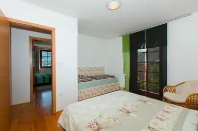 a bedroom with a bed and a chair and a window at Thirsty River Apartments in Bovec