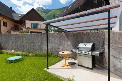 a bbq grill in a yard next to a wall at Thirsty River Apartments in Bovec