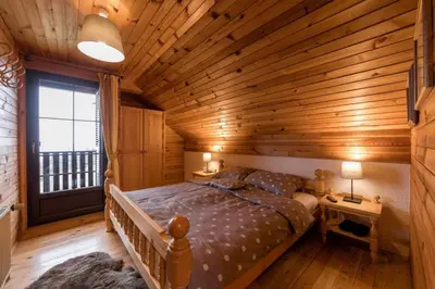 a bedroom with a bed in a wooden room at Cosy Hill Home Rucman With a Breathtaking View in Zgornja Pohanca