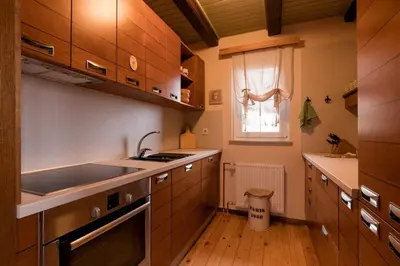 a kitchen with wooden cabinets and a sink and a window at Cosy Hill Home Rucman With a Breathtaking View in Zgornja Pohanca