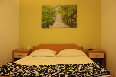 a bedroom with a bed with a painting on the wall at PONI NAKLO - Sobe Marinšek in Naklo
