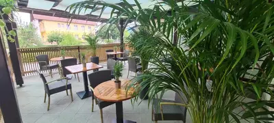 a patio with tables and chairs and plants at PONI NAKLO - Sobe Marinšek in Naklo