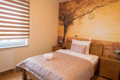 a bedroom with a bed with a tree painting on the wall at Guest House Goršič in Grosuplje