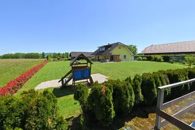a playground in a garden with a house in the background at Holiday Residence Ana in Boršt