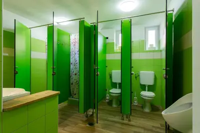 a green bathroom with two toilets and a sink at Yapka Rooms in Tolmin