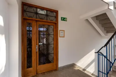 a wooden door in a white wall with a staircase at Yapka Rooms in Tolmin