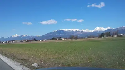 a field with snow capped mountains in the background at Apartma Rodica in Domžale