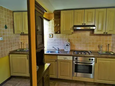 a kitchen with yellow cabinets and a stove top oven at Apartmaji Pr-Gujlu Sela nad Podmelcem 5220 TOLMIN in Podmelec