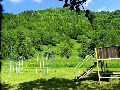 a swing set in a field with a hill in the background at Apartmaji Pr-Gujlu Sela nad Podmelcem 5220 TOLMIN in Podmelec