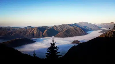 a view of a mountain valley with clouds and a tree at Apartmaji Pr-Gujlu Sela nad Podmelcem 5220 TOLMIN in Podmelec