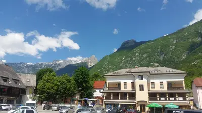 a building in a town with mountains in the background at Apartments Vila Bovec in Bovec