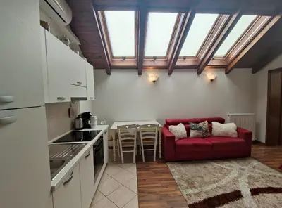 a living room with a red couch and a kitchen at Apartments Vila Bovec in Bovec