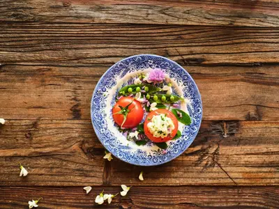 a plate of food with tomatoes and vegetables on a wooden table at HOTEL StDaniel in Štanjel