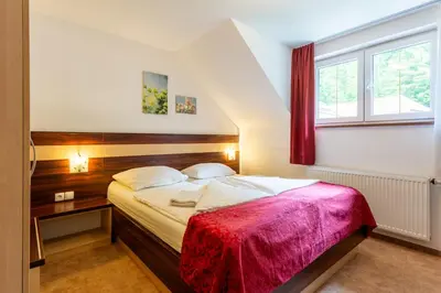 a bedroom with a bed with a red blanket at Guest House Hober in Prevalje