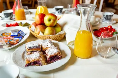 a table with a plate of cake and apples and orange juice at Guest House Hober in Prevalje
