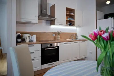 a kitchen with white cabinets and a sink and a vase of flowers at Codelli Deluxe City Centre Apartments in Ljubljana