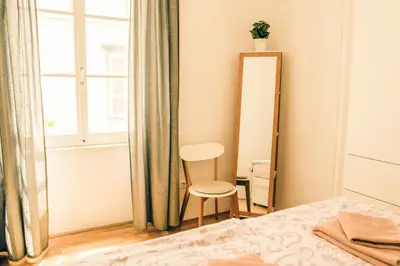 a bedroom with a bed and a chair next to a window at Codelli Deluxe City Centre Apartments in Ljubljana