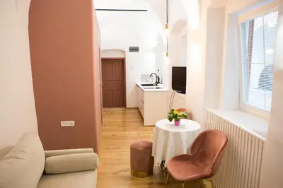 a living room with a table and chairs and a kitchen at Codelli Deluxe City Centre Apartments in Ljubljana