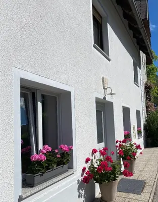 a white building with two windows with flowers in them at House Natura with garden in Bovec