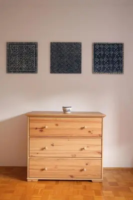 a wooden dresser in a room with three pictures on the wall at House Natura with garden in Bovec