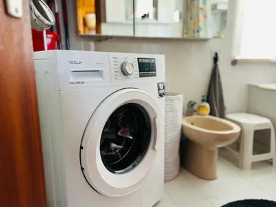 a white washing machine in a bathroom with a toilet at House for nature lovers in Medvode