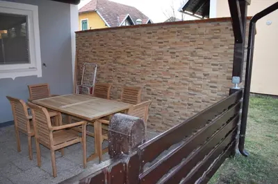 a wooden table and chairs and a brick wall at Borovnica Čatež in Čatež ob Savi