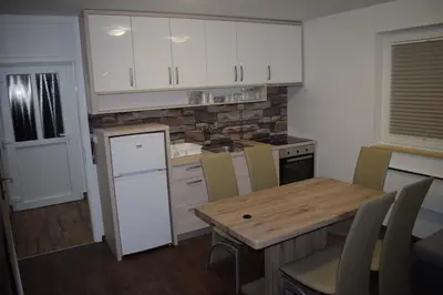 a kitchen with a wooden table and white cabinets at Borovnica Čatež in Čatež ob Savi