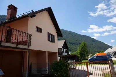 a house with a fence in front of a mountain at Apartma Lesjak 1 in Bovec