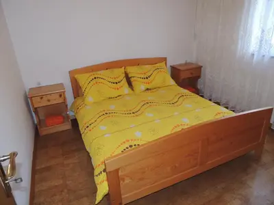 a bed with a yellow comforter and two night stands at Apartma Lesjak 1 in Bovec