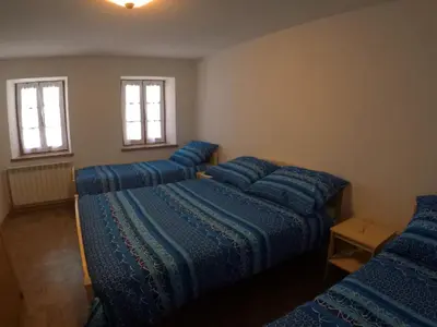a room with four beds with blue sheets and windows at Lesjakova Domačija in Bovec