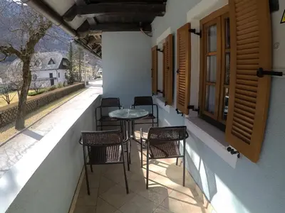 a patio with chairs and a table and windows at Lesjakova Domačija in Bovec