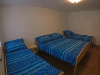 three beds in a room with blue sheets at Lesjakova Domačija in Bovec